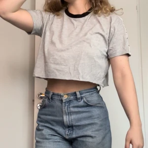 Grå Crop Top - Grå crop top med en remsa med ”NLY CLASS OF 1999” längs med axlarna, som ger t-shirten en cool street-style.
