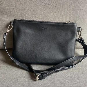 Axelremsväska  - Axelremsväska från Don Donna.  Mått: bredd 24cm, höjd 17cm, djup 2cm Använd ca 1-2 gånger. Fint skick! 