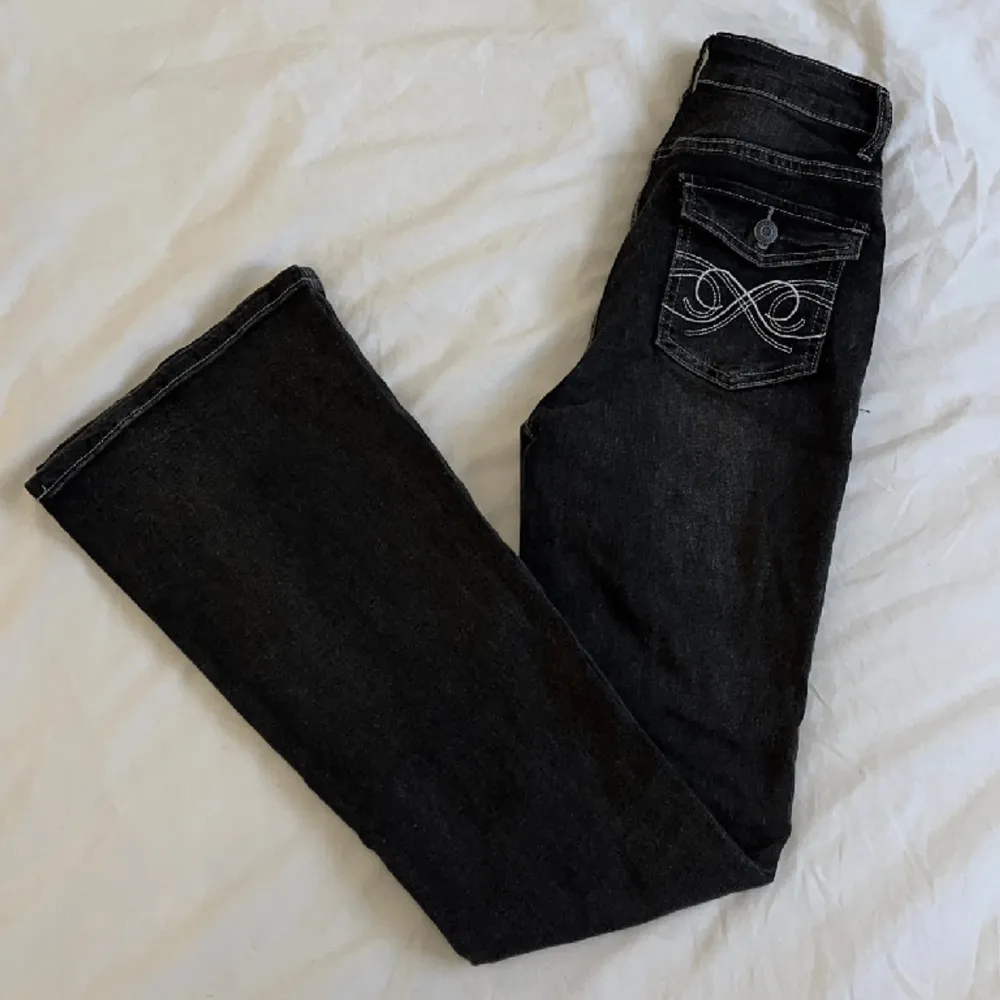 Bootcut jeans med detaljerade fickor. I färgen svart med toner av grå. De är i modellen bootcut. De är i passformen midwaist. Bra stretch. De är i nyskick. Storlek 34. 💗  Midjemått: 67 cm Innerbenslängd: 78 cm Totallängd: 106 cm Lårvidd: 22 cm. Jeans & Byxor.
