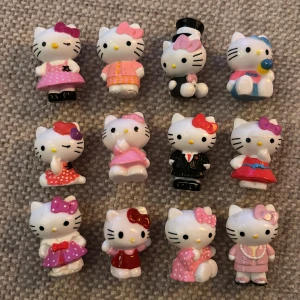 Hello Kitty-figurer - Små söta figurer av Hello Kitty i olika klädsel. Drygt en centimeter höga, se bild med jämförelse med finger. Gulliga att ha som dekoration på skrivbordet eller liknande. 