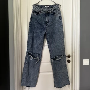 Blåa Jeans - Säljer mina högmidjade vida jeans från NA-KD, då dem ej kommer till användning. Använt ett få tal gånger. Jeansen är i storlek 38 men även uppklippta i benen, så passar mig som är ca 165 cm.  Nypris: 399kr