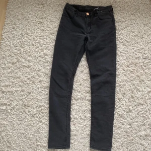Svarta skinny fit jeans - Ett par svarta skinny fit jeans i storlek 152. Byxorna har en knapp och dragkedja framtill samt fickor både fram och bak. Tillverkade i Bangladesh.