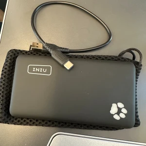 Powerbank - Anslutning: USB-C. Har en liten ficklampa, och väska + liten sladd för att ladda power bank medföljer. 