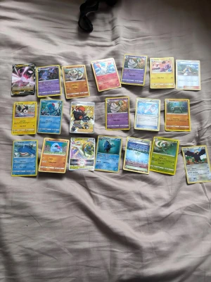 Samling Pokémonkort blandade typer - Säljer en samling Pokémonkort med olika typer och färger. Blandningen innehåller både vanliga och holografiska kort, med motiv av olika Pokémon från flera generationer. Perfekt för dig som vill utöka din samling eller börja spela Pokémon TCG.