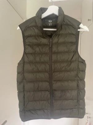 Olivgrön dunväst från uniqlo - Säljer denna sjukt snygga västen ifrån uniqlo. Storlek XS och använd en höst och vår. 