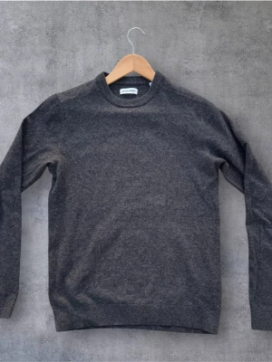 Mörkgrå stickad tröja Jack & Jones -  Mörkgrå stickad tröja från Jack & Jones i enkel och stilren design. Tröjan har rund halsringning, långa ärmar och ribbade muddar vid ärmslut och passar till det mesta.