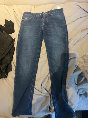 Boss jeans  - Snygga blå jean klassiska fem fickor. Jeansen har en lätt tvättad look och stängs med dragkedja och dubbla knappar. Perfekta för en avslappnad och trendig stil. Materialet är denim med stretch för extra komfort. Inte använda mycket sitter skönt skriv vid frågor ! 
