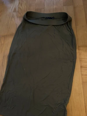 Mörkgrön midikjol - En enkel och stilren mörkgrön midikjol i mjukt material. Kjolen har en rak passform och bred midjeresår för bekväm känsla. Perfekt att matcha med en crop top eller hoodie för en avslappnad look.