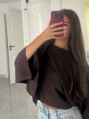 Brun loose croppad topp - Säljer en mörkbrun croppad topp med loose passform och vida ärmar. Toppen har en enkel, stilren design utan synliga detaljer och är perfekt för en avslappnad look. Materialet känns mjukt och bekvämt mot huden.