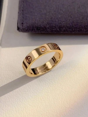 Guldfärgad ring med sten  - Snygg guldfärgad ring med rund form och infattad klar sten. Ringen har dekorativa gravyrer runt om och en polerad finish som ger ett lyxigt intryck. Perfekt accessoar för att lyfta din stil.