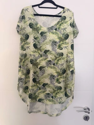 💚✨ Säljer en grön tunika/blus med vackert växt- och djurmönster ✨💚 - 💚✨ Säljer en grön tunika/blus med vackert växt- och djurmönster ✨💚  🌿 Skick: mycket bra 📏 Storlek: XL/XXL 📐 Mått: • Byst: 114 cm (stretchas upp till ca 130 cm) • Längd: 65 cm  💚 Tunikan är kortare framtill och längre baktill, med en rundad nederkant som ger en fin och smickrande passform.  🌸 Bekväm, luftig och perfekt till både vardag och fritid. Hör gärna av dig om du har frågor! 😊
