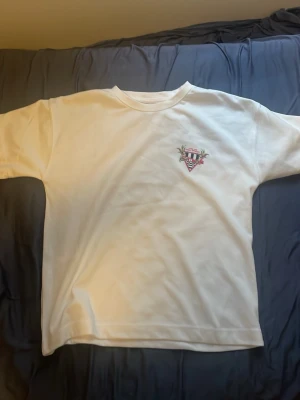 Vit t-shirt med Monaco-tryck - Original pris 500kr Säljer en vit t-shirt med coolt Monaco-inspirerat tryck på bröstet och ryggen. Trycket har palmer, racingbil och texten 'Monaco' i färgglada detaljer. Klassisk passform och rund hals, perfekt till jeans eller shorts.