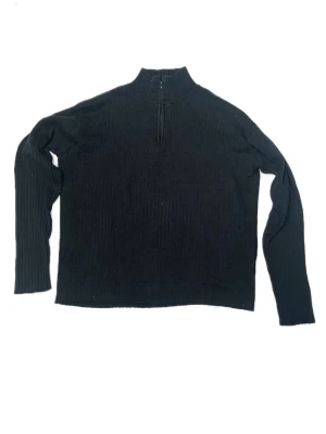 Svart tröja med halv dragkedja - Svart tröja med hög krage och halv dragkedja framtill. Tröjan har långa ärmar och ribbad struktur. Tunnt bomulls tyg. Storlek M. I använt skick därav lite ljusare svart (solblekt) men fortfarande fin.