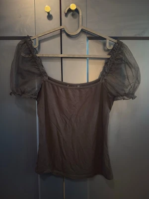 Svart topp med puffärmar från SHEIN - Snygg svart topp från SHEIN med transparenta puffärmar i mesh och rak halsringning. Kroppsdelen är i mjuk bomullsmix och toppen har en feminin och trendig look som passar perfekt till jeans eller kjol. Storlek XS passar S också 