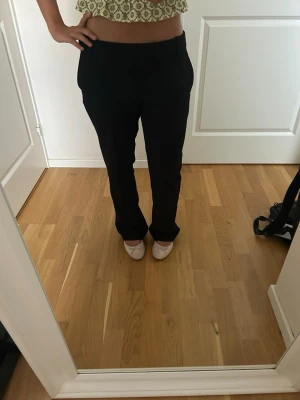 Svarta raka kostymbyxor - Säljer ett par svarta kostymbyxor med rak passform och låg midja. Byxorna har klassisk look och är perfekta till en snygg outfit. 