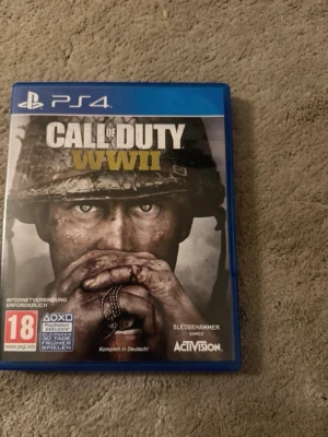 Call of Duty WWII till PS4 - Säljer spelet Call of Duty WWII till PlayStation 4. Omslaget är blått och spelet är ett actionfyllt förstapersonsskjutare med kampanj, multiplayer och zombies-läge. Texten på fodralet är på tyska och spelet är PEGI 18.