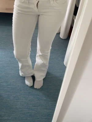 Vita bootcut jeans Cheap Monday - Säljer ett par vita bootcut jeans från Cheap Monday med cool logga på bakfickan och klassisk femficksdesign. Jeansen har hyfsat låg midja och är tillverkade i stretchigt denimtyg för skön passform.