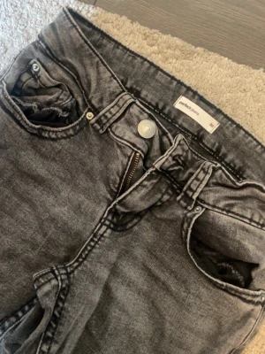 Grå jeans från Gina tricot - Säljer ett par grå cargojeans med tvättad look och flera stora fickor på benen. Jeansen har dragkedja, knappstängning. Säljer då dem ej kommer till användning längre 