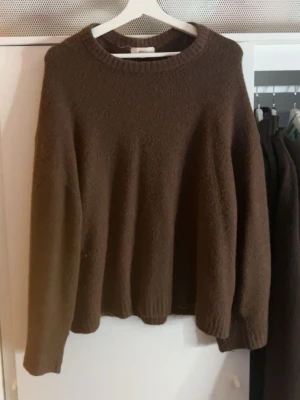 Brun stickad tröja från Gina Tricot - Mysig brun stickad tröja från Gina Tricot i ullblandning. Tröjan har rund halsringning, långa ärmar och ribbstickade muddar vid ärmslut och nederkant. Perfekt för kyliga dagar. L men passar som M, perfekt för höst 