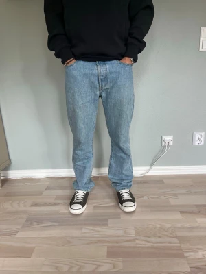 Levi’s 501 Jeans Light Wash W30 L30 - Levi’s 501 i ljusblå denim med klassisk straight fit. Tidlös modell med knappgylf och klassiska Levi’s-detaljer. En mångsidig jeansmodell som passar perfekt till både t-shirt, hoodie, skjorta eller stickat.  Skick: fint skick, inga hål eller fläckar Storlek: W30 L30 Passform: 501 / straight fit