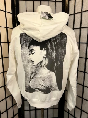 Ariana Grande hoodie zip NWT XS 🤍🔥 - 🤍 ARIANA GRANDE HOODIE – HELT NY MED TAGS! 🤍  Så snygg vit zip-hoodie med diskret Ariana Grande-text framtill och ett stort ikoniskt fototryck över hela ryggen 🔥 Ariana är ständigt aktuell och den här lär inte ligga kvar länge!  ✨ Helt ny med tags – NWT ✨ Storlek XS ✨ Från H&M ✨ Dragkedja och stor luva ✨ Mjuk fleeceinsida ✨ Perfekt merch-, pop girl- och oversized look  