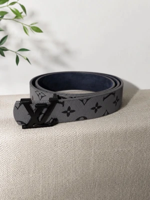 Grått bälte - Snyggt grått bälte med svart spänne och klassiskt monogrammönster. Perfekt accessoar för att lyfta din outfit med en exklusiv touch. Bältet har en stilren design och passar till många olika looks.
