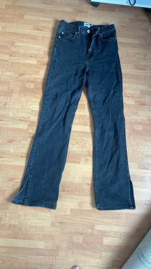 Svarta high-waist utsvängda jeans med slits - Snygga svarta högmidjade jeans med lite utsvängda ben och slits nertill. Väldigt bra skick och de är också mycket enkla att styla.