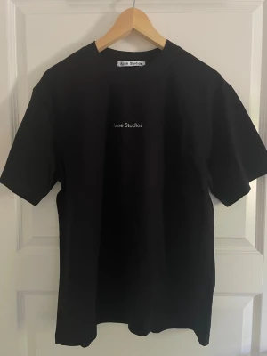 Acne studios T-shirt svart  - Väldigt fin T-shirt ifrån acne studios i nyskick. Tröjan är helt oanvänd och har inga defekter alls. Tröjan är true to size alltså sitter som en M. Trycket är i ett reflex material så den skiner när det lyser på den. Har du frågor är det bara att skriva. 