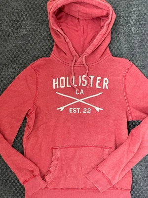 Röd hoodie från Hollister - Säljer nu denna sjukt snygga Vintage 2000s Hollister hoodie! Passar till allt och har en perfekt passform. Säljs ej längre i butik och är därav mycket eftertraktad😊 passar M perfekt ! Skriv vid funderingar 🤝