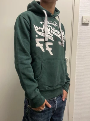 Superdry hoodie - Snygg hoodie ifrån Superdry i storlek S. Lite sliten vid kragen (se bild 4) annars bra skick. Modellen är 173cm, 64kg. Pris kan diskuteras!!