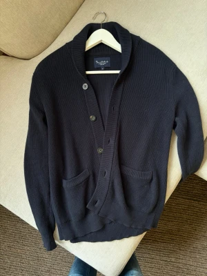 Bondelid mörkblå stickad cardigan – S - Mörkblå stickad cardigan från Bondelid i storlek S. Klassisk modell med sjalkrage, knappstängning framtill och två framfickor. Kraftigare stickning som passar perfekt till höst och vinter.  Fint begagnat skick utan några tydliga större defekter, se bilder.  