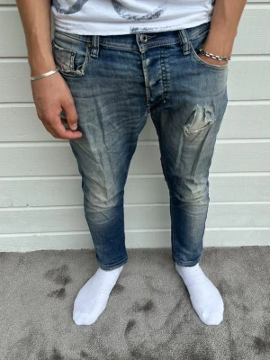 Diesel jeans blå  - Hej! Riktigt feta diesel jeans säljes. Modellen på bilden är 183cm och väger 68kg. Storlek: W31/L30 med passformen slim+. Jeansen är slitna där fram som syns på första bild blandannat, jeansen är också slitna i grenen. Syns inte vid användning och påverkar inte användningen att de är lite slitna i grenen men det går enkelt att fixa för den som har tid och lust. Hör gärna av er vid intresse! Mvh DC ♦️