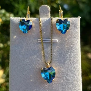 Smyckesset hjärtan kristall - Smyckesset, brisyrkrok och hänge i guldpläterad mässing med hjärtformade kristaller. Heart 11x10mm, färg Bermuda Blue. Senare bild visar andra färger som finns i lager. Jag skickar endast spårbart, fast pris, samfraktar. Besök gärna mina övriga annonser.  Till mina smycken använder jag kristaller från Preciosa, Aurora och Swarowski.