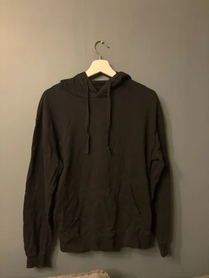 Svart hoodie  - En enkel svart hoodie huva och dragsnören. Hoodien har en stor magficka framtill och ribbade muddar vid ärmslut och nederkant. 
