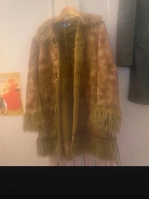 Vintage penny-lane jacka  - Säljer en brun penny lane kappa i fuskpäls med fluffiga detaljer vid krage, ärmslut och nederkant. Kappan har ett retroinspirerat mönster och stängs med knappar framtill. Köpt vintage i Portugal, så väldigt unik! Perfekt för dig som vill sticka ut med en cool och mysig jacka i höst och vinter💘 skulle säga att den passar en XS-L beroende på hur man vill att den ska sitta, passar mig bra som är S/M.
