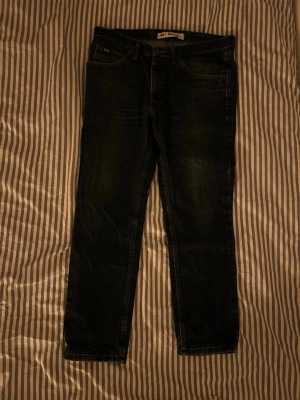 Mörkblå raka jeans - Säljer ett par mörkblå jeans med rak passform och klassisk femficksdesign. Jeansen har normal midja och subtila slitningar för en avslappnad look. Tillverkade i denim med snygga sömmar och bälteshällor. Perfekta till vardagsstilen.