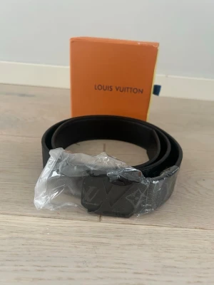 Svart Bälte - Snyggt svart bälte med klassiskt monogrammönster och en fin logga på metallspännet. Bältet har en stilren design och kommer i originalförpackning. Perfekt accessoar för att lyfta din outfit.