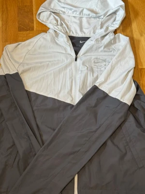 Nike Miller Vindjacka  - Nike Air-logo på bröstet • Huva med dragsko • Dragkedja framtill • Lätt och bekväm modell • Använd, men i fint skick ✨ • Säljs utan originalpåse 📦  📍 Kan mötas i Stockholm 🤝 📦 Kan även skickas!
