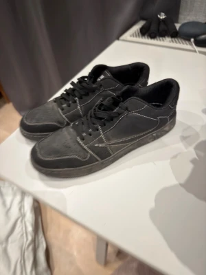 Svarta sneakers med vita sömmar - Säljer ett par svarta sneakers med kontrasterande vita sömmar och klassisk snörning. Skorna har en låg profil och är tillverkade i syntetmaterial med mockadetaljer. Perfekta för dig som gillar en stilren och enkel look. Sunkiga skor pris kan diskuteras
