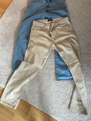 Beige & Blåa  jeans från Jack & Jones - Snygga beige jeans från Jack & Jones i modellen Relaxed Chris. Storlek 30/32.  Klassisk femficksdesign, raka ben och knappgylf. Perfekta för dig som gillar en avslappnad och stilren look. Tillverkade i mjukt bomullsmaterial.     De blåa jeansen heter Loose Eddie och har storlek 29/32      200:-/ par