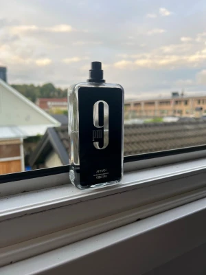 Afnan 9PM parfym  - Afnan 9PM parfym i en stilren, rektangulär glasflaska med svart etikett och stor silverfärgad siffra 9 på framsidan. Flaskan rymmer 100ml och har en modern, minimalistisk design som passar perfekt på parfymhyllan.