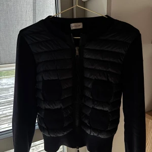 mörkblå cardiganjacka från Moncler - Snygg mörkblå cardiganjacka från Moncler med quiltad front och fyra fickor. Jackan har rund halsringning, dragkedja framtill och Moncler-logga på ärmen. Materialmix med stickade ärmar och rygg samt vadderad front ger en modern look. Jag har knappt använt jackan då jag tycker den är lite för liten. Det går att få ner priset!!💕💕💕💕💕💕