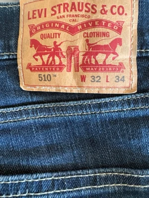 Levi's 510 Slim Fit Jeans blå - Säljer ett par mörkblå Levi's 510 Slim Fit jeans med klassisk femficksdesign och snygga kontrastsömmar. Jeansen har en smal passform och är tillverkade i slitstarkt denimtyg. Perfekta för dig som gillar en modern och stilren look.