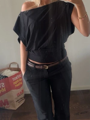 Svart topp - Snygg svart offshoulder topp med lös passform upptill och bredare band nedtill som sitter åt. Toppen är ärmlös och har en modern, stilren look som passar perfekt till både jeans och kostymbyxor. Fungerar både att ha som off shoulder och vanligt!
