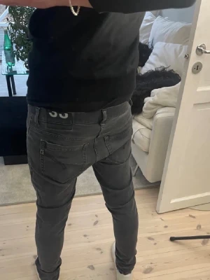 Mörkgrå dondup slim fit jeans o svarta dond up jeans  - Säljer ett par mörkgrå slim fit jeans med klassisk femficksdesign och låg midja. Jeansen har smala ben och diskreta sömmar, perfekta för en clean och modern look. Passar dig som gillar en tightare passform.