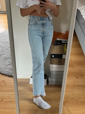 Ljusblå Ribcage Straight Levi's jeans  - Levis Ribcage modell i ljusblå. De är i 25/28, alltså 25 i midjan och och 28 i längd.  Mina tidigare favoritbyxor men jag har växt ur dem! Så sköna och stretchiga men ändå tjockt tyg. De är raka/vida högmidjade jeans i ankelläng som knäpps med knappar. 