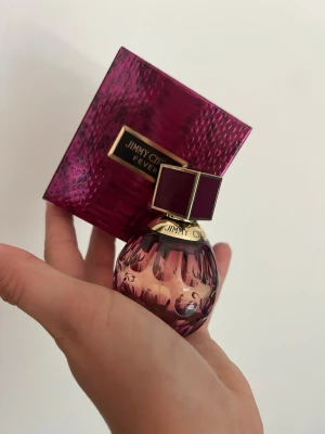 Jimmy Choo Fever parfym 40 ml - Jimmy Choo Fever är en lyxig parfym i en mörklila, rund glasflaska med gulddetaljer och en fyrkantig lila kork. Förpackningen är matchande mörklila med gulddetaljer och ormmönster. Doften är intensiv och elegant, perfekt för dig som vill sticka ut.