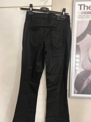 Svarta bootcut jeans - Säljer ett par svarta bootcut jeans med mellan midja och klassiska fem fickor. Jeansen har utsvängda ben och stängs med knapp och dragkedja. Perfekta för dig som vill ha en tidlös och snygg look. Aldrig använda 