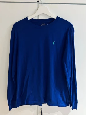 Blå långärmad tröja Polo Ralph Lauren - Snygg blå långärmad tröja från Polo Ralph Lauren. Väldigt gott skick, knappt använd. Storleken XL (18-20) är en tonårsstorlek, så snarare som en normal S eller 170. Längd på tröjan: 65 cm, bredd: 40 cm.