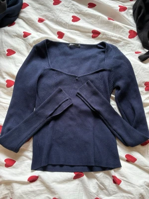 Mörkblå ribbad topp Gina Tricot - Snygg mörkblå ribbad topp från Gina Tricot med lång ärm och v-ringad hals. Tröjan har även slits längst ner på armen